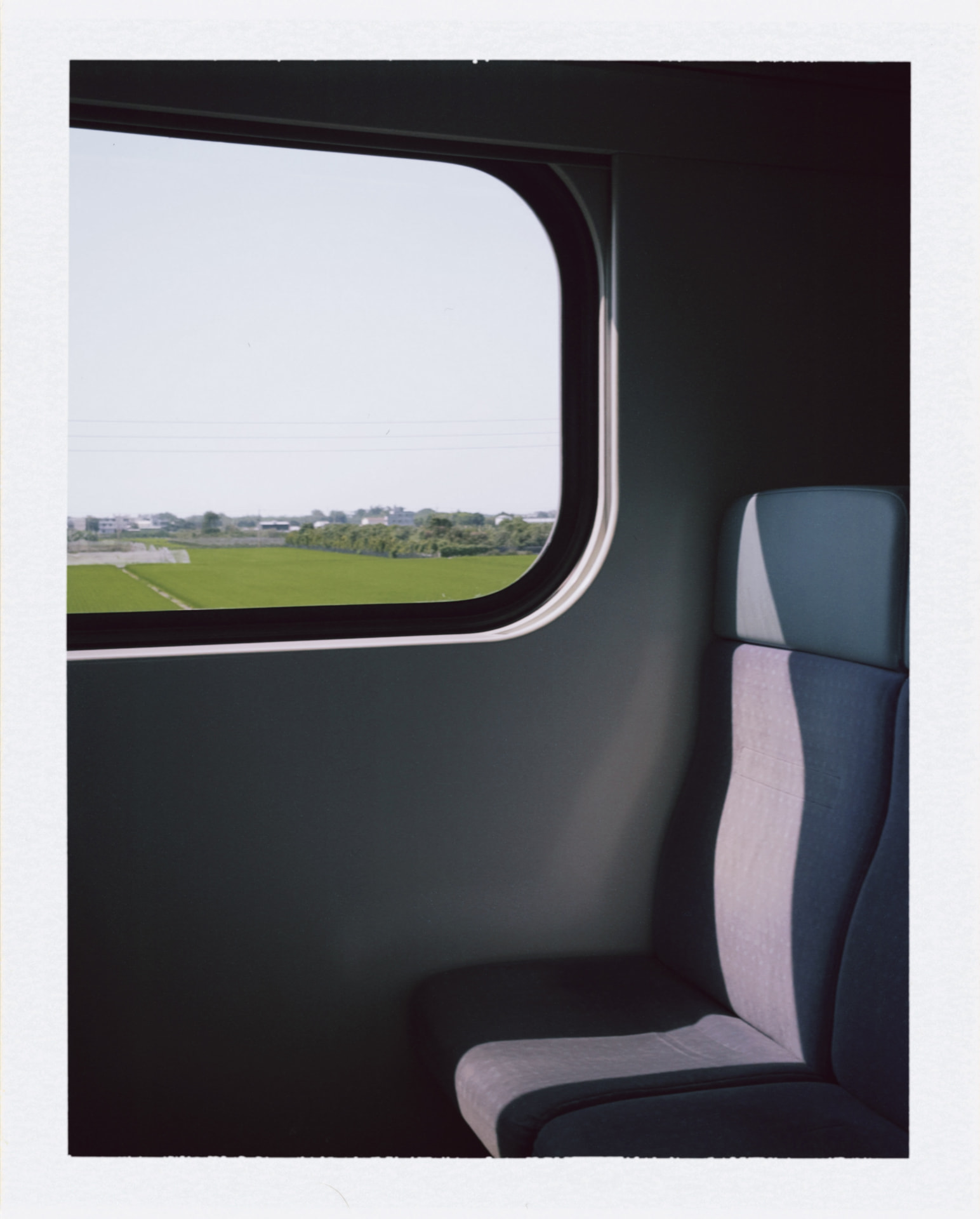 Train interior beside a window overlooking green fields